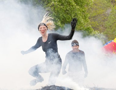 Stockholm, İsveç - 14 Mayıs 2016: sarışın kadın üzerinden atlama ateş ve engel yarışta zor Viking olay İsveç ' te 14 Nisan 2016 duman