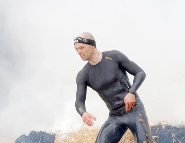 Stockholm, İsveç - 14 Mayıs 2016: 14 Nisan 2016 'da İsveç' te düzenlenen engelli yarışında siyah elbiseli kaslı bir adam yangın ve duman arasında koşuyor.