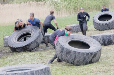 STOCKHOLM, SWEDEN - MAY 14, 2016: Group of men and woman struggling to tip a large tractor tire obstacle in the obstacle race Tough Viking Event in Sweden, April 14, 2016
