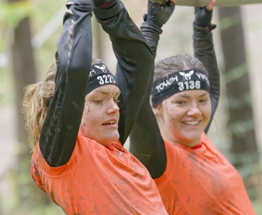 STOCKHOLM, SWEDEN - MAY 14, 2016: Two smiling woman with mud in her face trying to maintain her balance on a slack rope in the obstacle race Tough Viking Event in Sweden, April 14, 2016