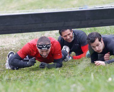 Stockholm, İsveç - 14 Mayıs 2016: İsveç 'te 14 Mayıs 2016' da zorlu Viking yarışında dikenli tellerin altında sürünen bir grup gülen adam