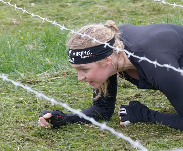 瑞典斯德哥尔摩 2016年5月14日 2016年5月14日在瑞典举行的硬墙越野赛 Tough Viking Event 金发女子爬到草坪上的铁丝网障碍物下 — 图库照片
