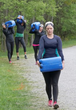 STOCKHOLM, SWEDEN - MAY 14, 2016: Group of woman and men carry a heavy water can in the forest in the obstacle race Tough Viking Event in Sweden, May 14, 2016
