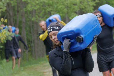 STOCKHOLM, SWEDEN - MAY 14, 2016: Group of woman and men carry a heavy water can in the forest in the obstacle race Tough Viking Event in Sweden, May 14, 2016