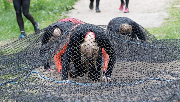 Grupp av kvinnor krypa under ett netto hinder — Stockfoto