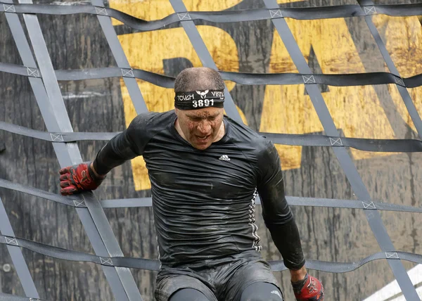 瑞典斯德哥尔摩 2016年5月14日 2016年5月14日在瑞典举行的越野赛 Tough Viking Event 被泥土覆盖的人爬上了一个障碍网 — 图库照片