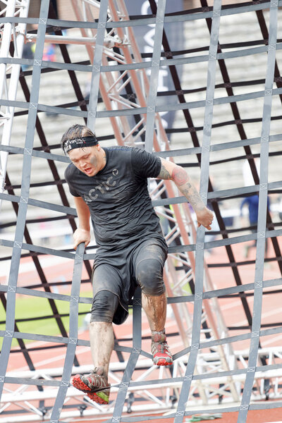 Мужчины взбираются на препятствие
