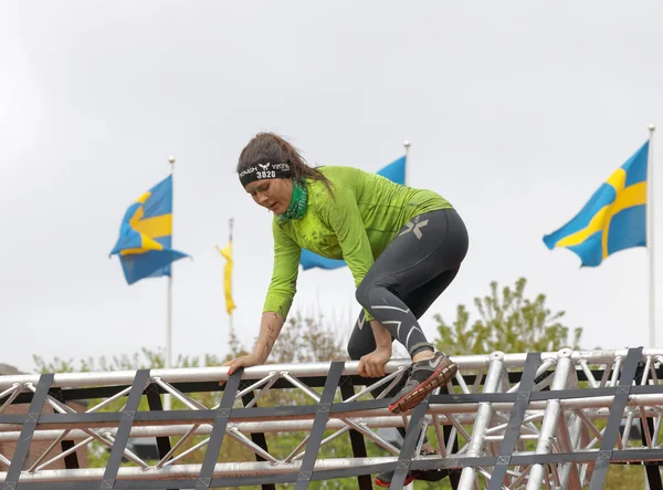 Vrouw klimmen een netto obstakel, Zweedse vlaggen op de achtergrond — Stockfoto