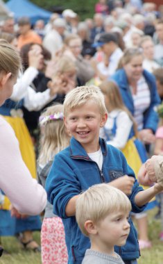 Gülümseyen genç sarışın çocuk etrafında dans direği
