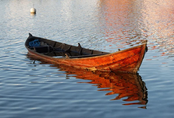 Houten roeiboot in warm avondlicht deels gevuld met water — Stockfoto