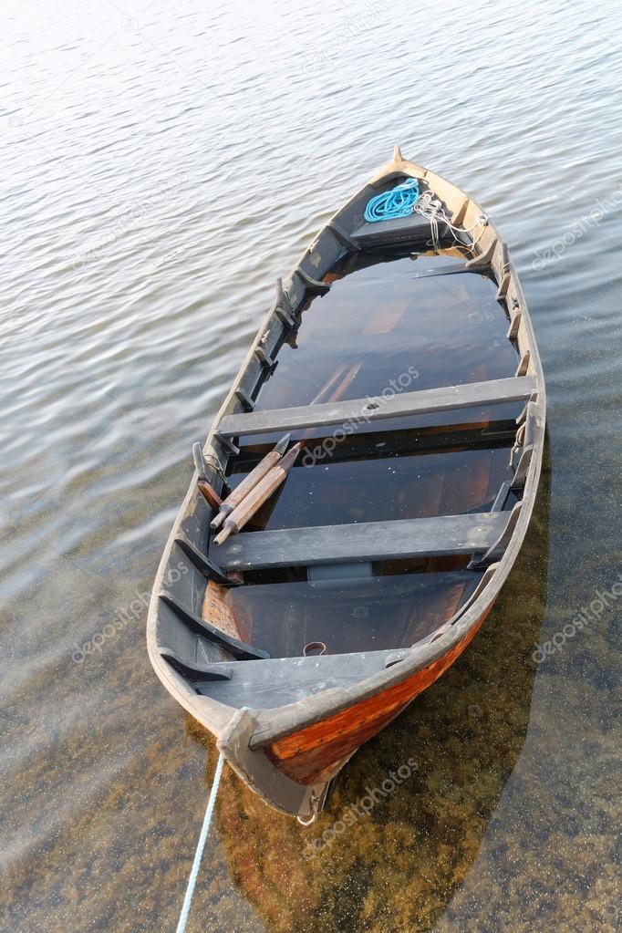 Wooden rowboat in warm evening light partly filled with water Stock Photo  by ©Hans_Chr 115063732