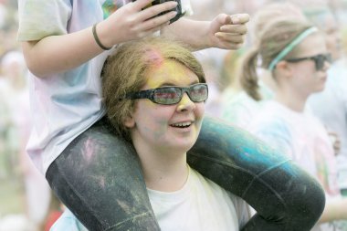 Stockholm, İsveç - 22 Mayıs 2016: 22 Mayıs 2016 'da İsveç' te düzenlenen Renkli Koşu etkinliğinde omuzlarında arkadaşıyla birlikte renk pudrasıyla kaplanmış genç bir kadın