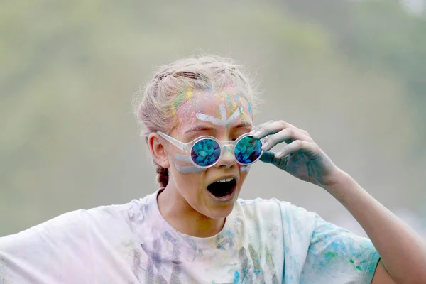 Mujer joven sorprendida con gafas de sol cubiertas con polvo de color — Foto de Stock