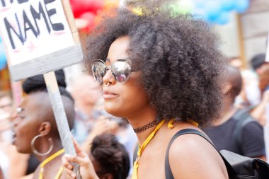 Kadın afro saçlı ve bir işaret gurur içinde tutan güneş gözlüğü 