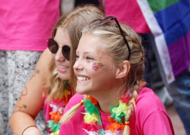 İki genç mutlu sarışın kız gülümsüyor, renkli arka plan