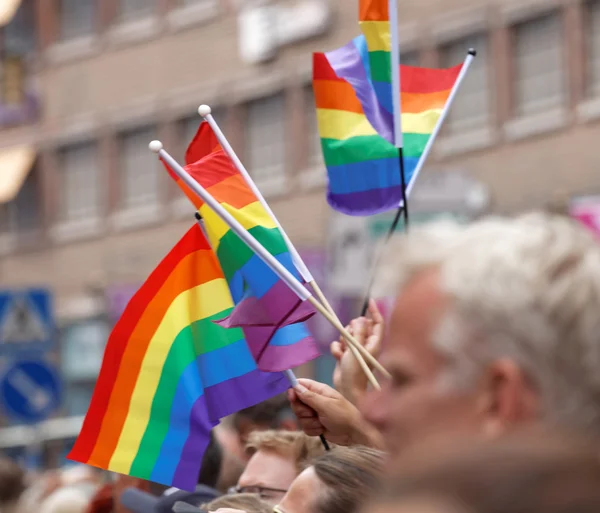 Manos renunciando a la bandera del orgullo del arco iris — Foto de Stock