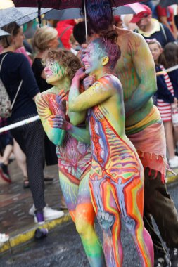 Stockholm, İsveç - 30 Temmuz 2016: Renkli vücut boyalı kızlar gülümseyen, 30 Temmuz 2016 'da İsveç' in Stockholm kentinde düzenlenen Onur Yürüyüşü 'nde şemsiye tutan bir oğlan