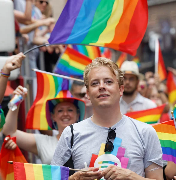 Uśmiechnięty mężczyzna Blondynka, mnóstwo rainbow Pride flagi w tle — Zdjęcie stockowe