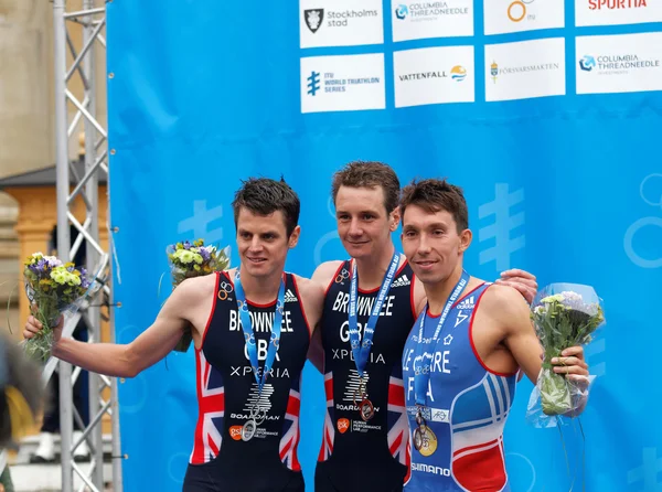 The smiling medalist triathletes drinking champagne on the podiu — Stock Photo, Image