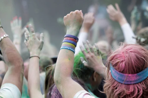 Público feliz con brazos en el aire y polvo de color en el aire — Foto de Stock