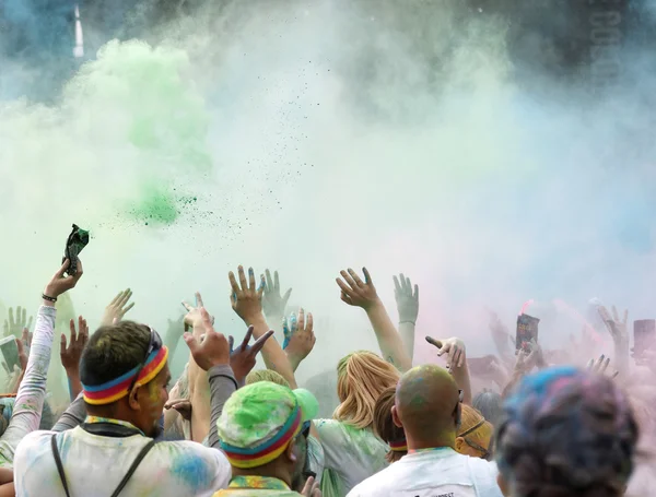Público feliz con brazos en el aire y polvo de color en el aire — Foto de Stock