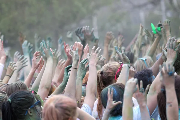 Público feliz com braços no ar e pó de cor no ar — Fotografia de Stock