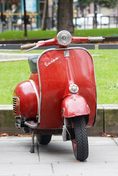 Red retro vespa scooter parked in the park — Stock Photo, Image