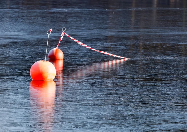 Två orangefärgade bojar återspeglar i is — Stockfoto