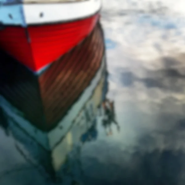 Barco vermelho desfocado refletindo na água — Fotografia de Stock