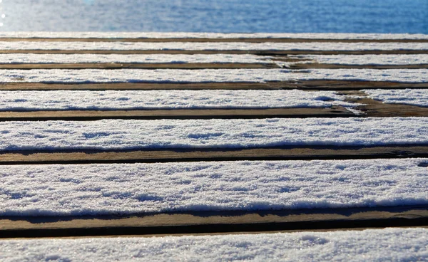 Bro av planka med snö och havet — Stockfoto