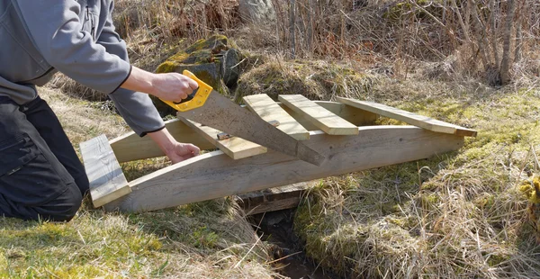 Man een kleine gebogen houten brug gebouw — Stockfoto