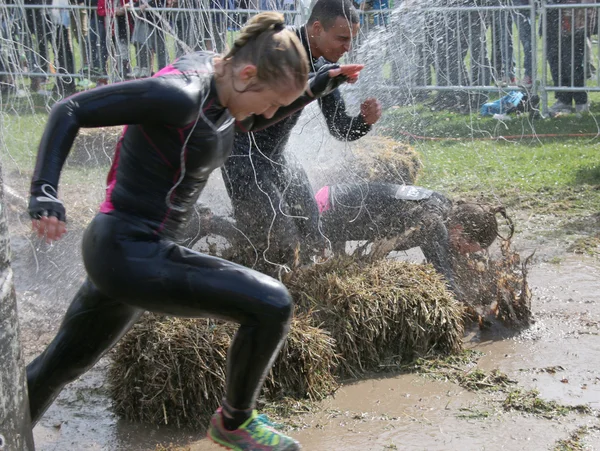 Mujer y hombre corriendo, una mujer ha caído en el barro — Foto de Stock