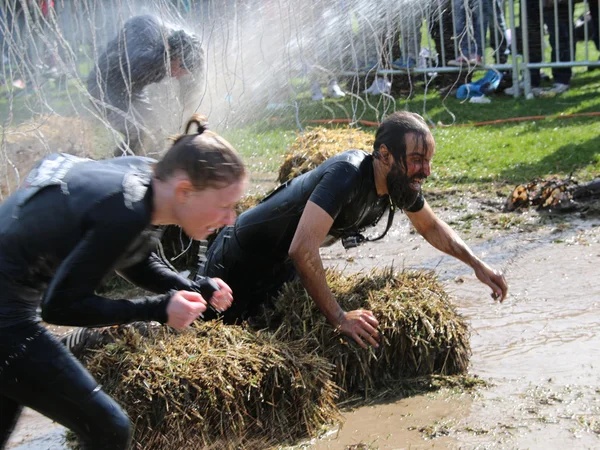 Mujer y hombre luchando para atravesar el barro, chorreados con wat —  Fotos de Stock