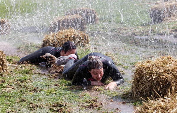 Zwei Frauen krabbeln im Schlamm zwischen Heugarben — Stockfoto