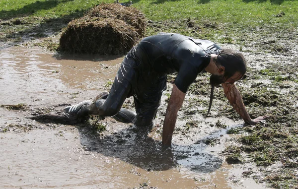 Hombre luchando para atravesar el barro de rodillas — Foto de Stock