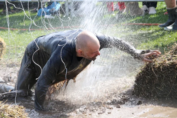 Hombre luchando para atravesar el barro, chorreado con agua, electr —  Fotos de Stock