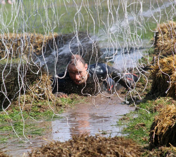 Um homem aterrorizado rastejando na lama — Fotografia de Stock