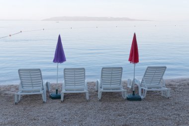 Dört boş şezlong ve şemsiye