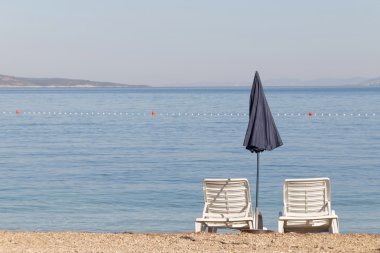 Two empty deck chair and a blue parasol