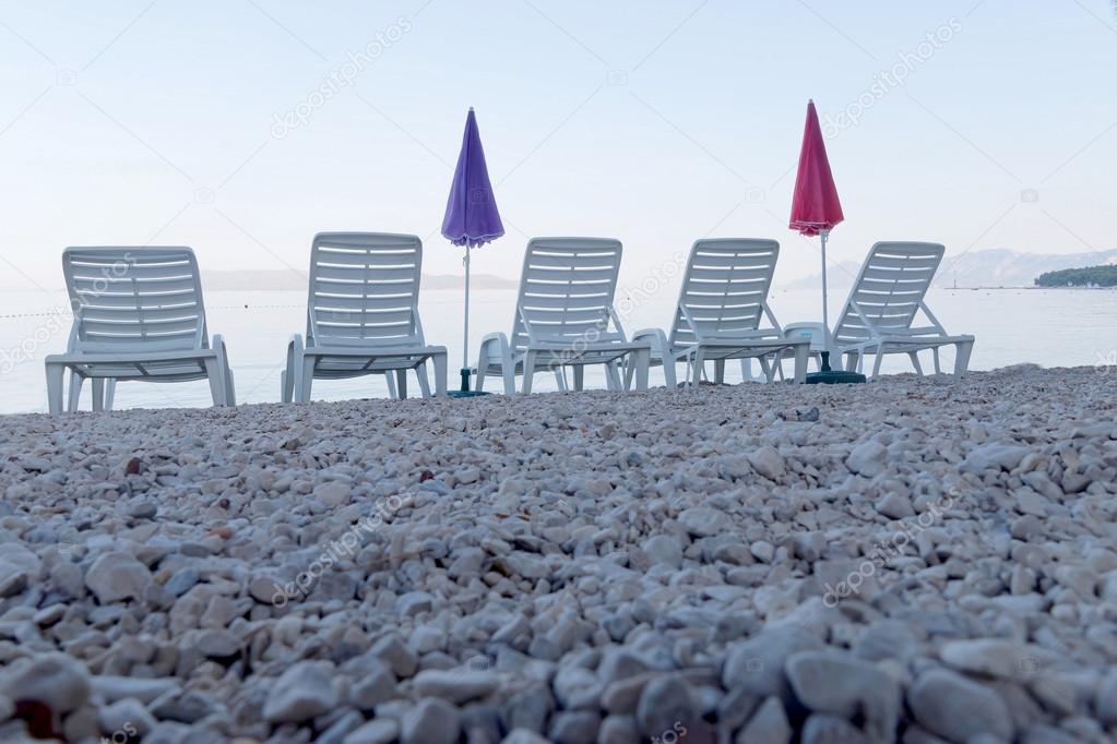 Five empty deck chair and parasol from a low angle