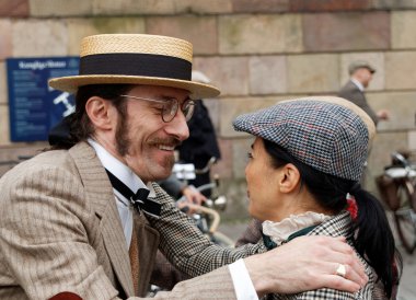 Smiling man in straw hat hugging elegant lady wearing old fashio