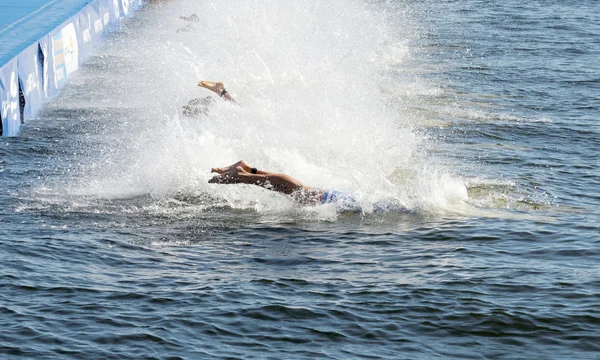 Manliga simning konkurrenter hoppa i vattnet — Stockfoto