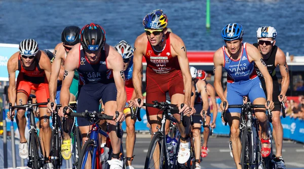 Stuggling, muscular triathlon competitors cycling uphill — Stock Photo, Image