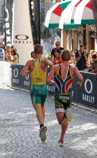 Achteraanzicht van twee kleurrijke triathleten lopen bergafwaarts — Stockfoto