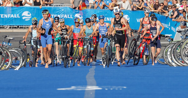 Chaotic scene with running triathletes with bicycles in the tran