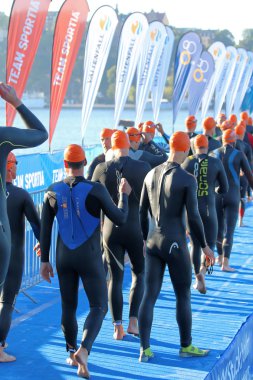 Stockholm - 23 Ağustos 2015: Stockholm 'de düzenlenen Itu Dünya Triatlonu etkinliğinde siyah mayo ve turuncu mayo giyerek başlangıç alanına yürüyen büyük bir erkek triatlet grubu