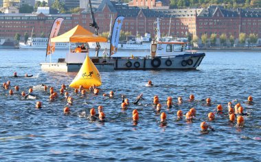 Büyük bir grup erkek yüzücüler turuncu banyo kapaklar giyiyor