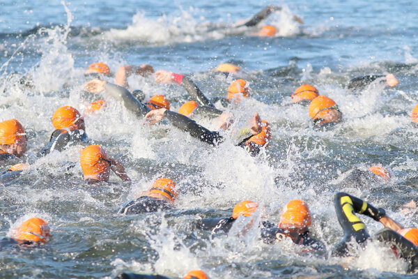 Swimming chaos of male swimmers wearing orange bathing caps