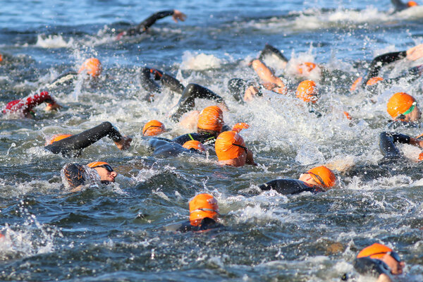 Swimming chaos of male swimmers wearing orange bathing caps