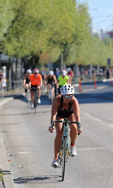 斯德哥尔摩 2015年8月23日 骑自行车的女人 戴着黑色的坦克顶和白色的头盔 之后是竞争对手 2015年在斯德哥尔摩举行的Itu世界铁人三项赛的背景树 — 图库照片